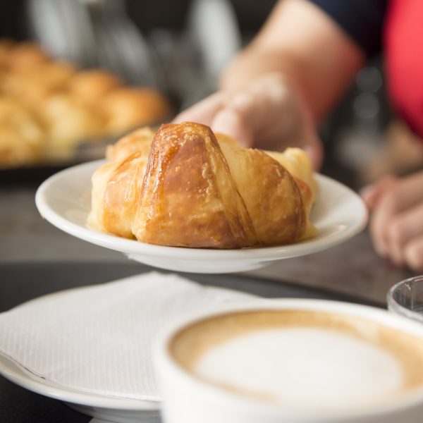 close up waitress s hand offering baked croissant