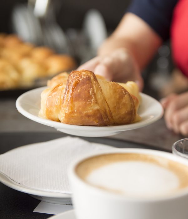 close up waitress s hand offering baked croissant
